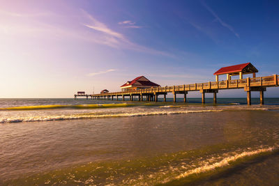 Built structure on beach against sky during sunset