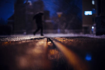 Blurred motion of person walking on illuminated street at night