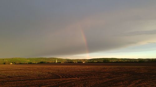 Scenic view of rainbow over field against sky
