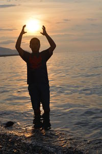 Man standing on beach against sky during sunset