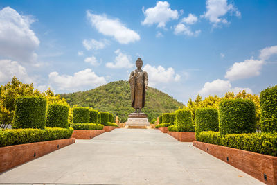 Statue against trees and plants against sky