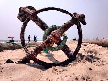 Rusty anchor on beach against clear sky