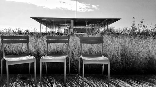 Chairs by grass against sky