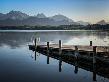 Wooden posts in lake against sky