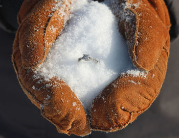 Close-up cropped hand holding engagement ring with snow