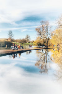 Reflection of bare trees in lake against sky