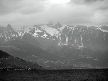 Scenic view of sea by snowcapped mountains against sky