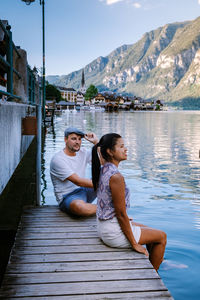 Couple sitting on lake by mountains