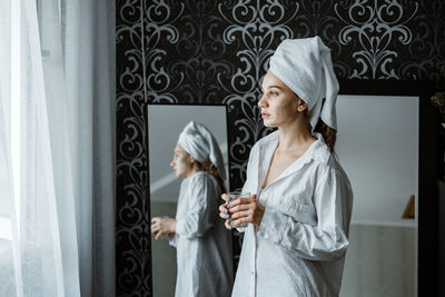 Woman with umbrella standing against curtain