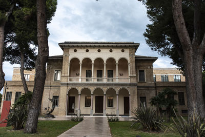 Facade of old building against cloudy sky