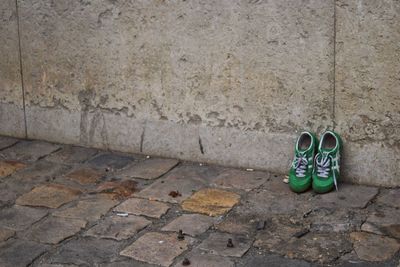 Green shoes by wall on sidewalk
