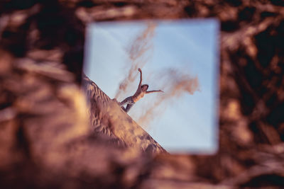 Reflection of woman spilling sand in mirror