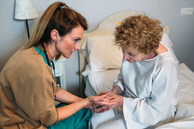Nurse consoling senior patient in hospital
