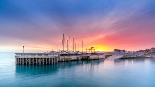 Sailboats in sea against sky during sunset