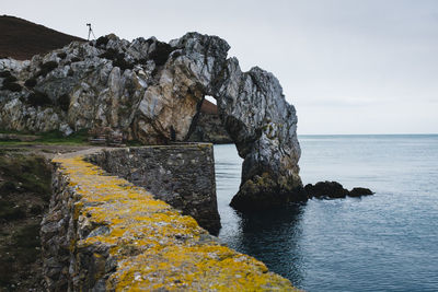 Rock formation by sea against sky