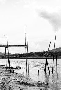 Wooden posts on beach against sky