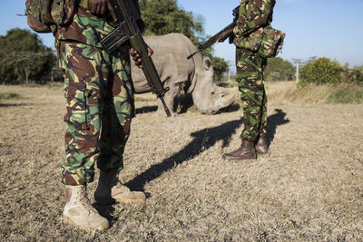 Soldiers standing by rhinoceros on field