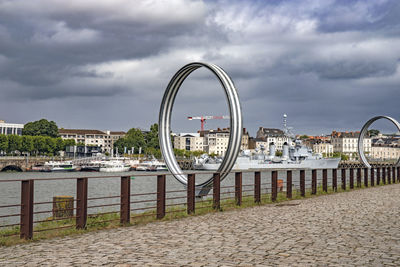 Ferris wheel by river against sky in city