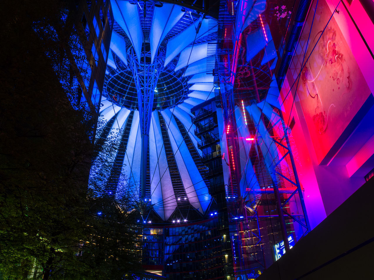 LOW ANGLE VIEW OF ILLUMINATED LANTERNS HANGING BY BUILDINGS AT NIGHT