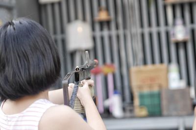 Rear view of girl aiming with toy gun