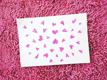 Close-up of paper with pink heart shapes on rug