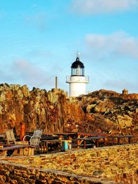 Lighthouse by building against sky