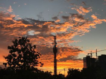 Silhouette trees on landscape against sky at sunset