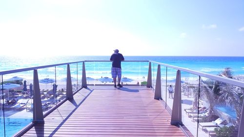 Rear view of man looking at sea against sky