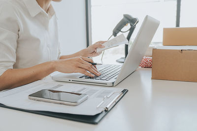 Midsection of woman using laptop on table