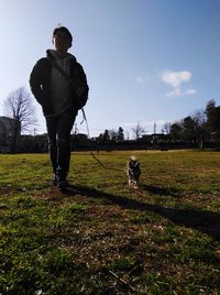 Rear view of man standing on field against sky