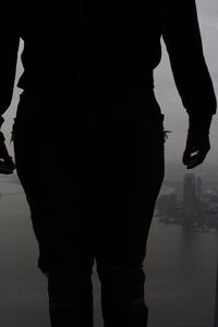 Low section of silhouette man standing at beach