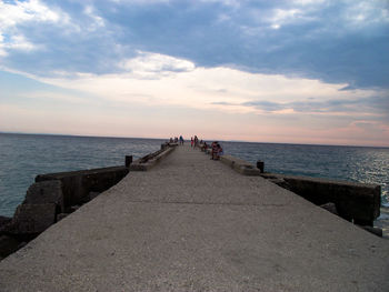 Group of people on pier over sea against sky