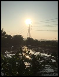 Electricity pylon on field against clear sky during sunset