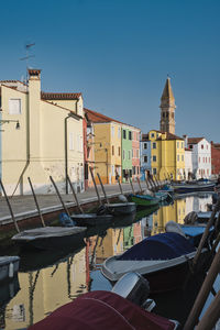 Boats moored in canal by buildings in city