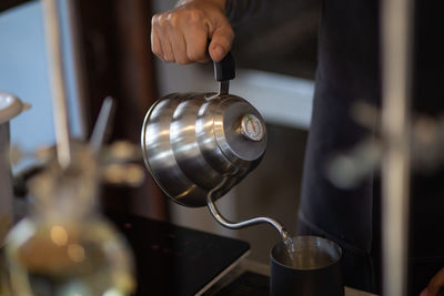 Midsection of man pouring coffee in kitchen