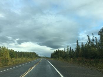 Road by trees against sky