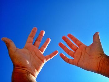 Close-up of hands against clear blue sky