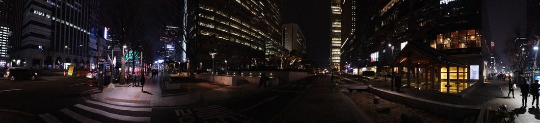 Illuminated street amidst buildings in city at night