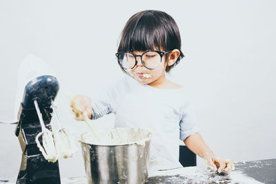 Cute girl eating cake against white background