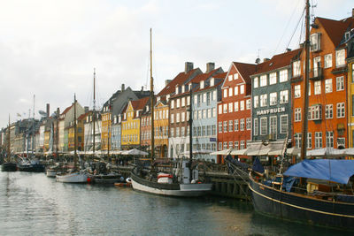 Sailboats moored on canal amidst buildings in city