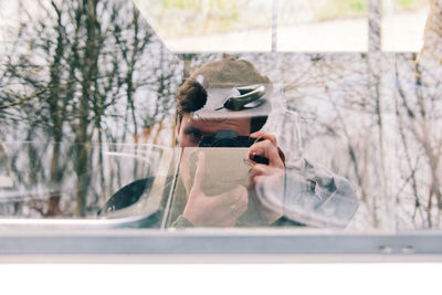 Rear view of woman photographing through window