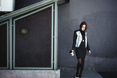 Young woman standing against gray wall