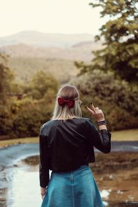 Rear view of woman standing on road against trees