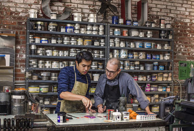 Workers mixing colors using ink knife on table at workshop