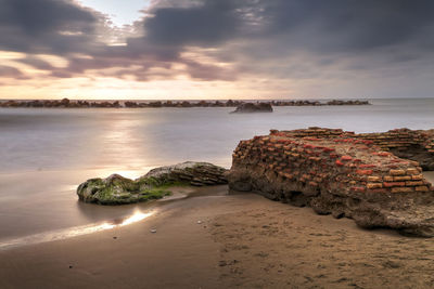 Scenic view of beach against cloudy sky