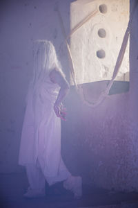 Woman performing by window in abandoned building