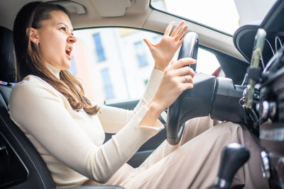 Young woman using mobile phone while sitting in car