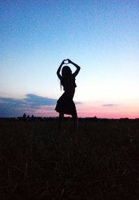 Silhouette woman standing on field against sky during sunset