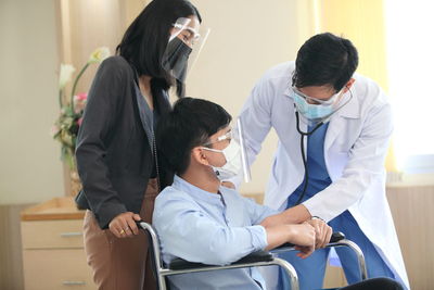 Doctor examining man sitting on wheelchair in hospital