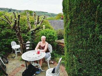 Young woman sitting on table against trees